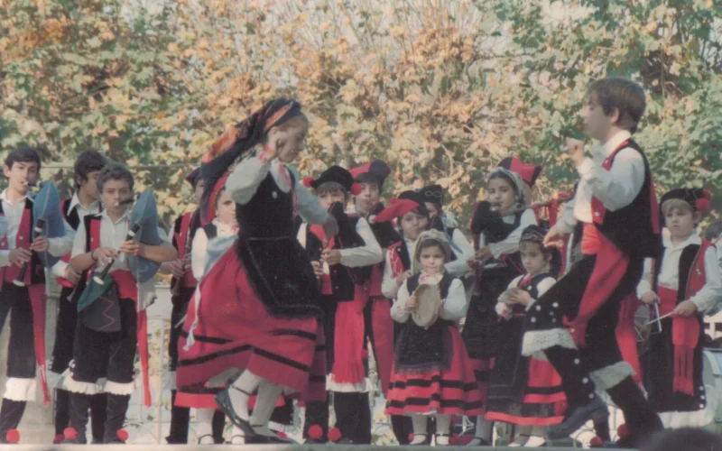 Grupo de Os Chaneiros tocando e bailando música tradicional galega co traxe típico vermello e negro