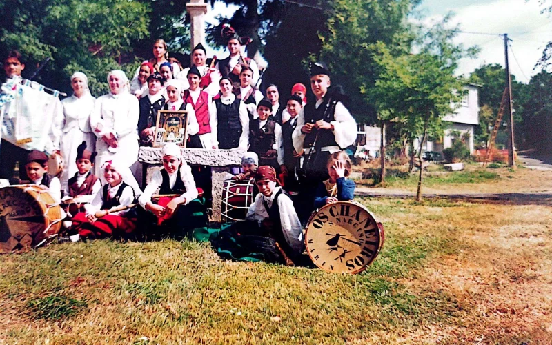 Grupo de folclore galgo posando xunto a un cruceiro no rural